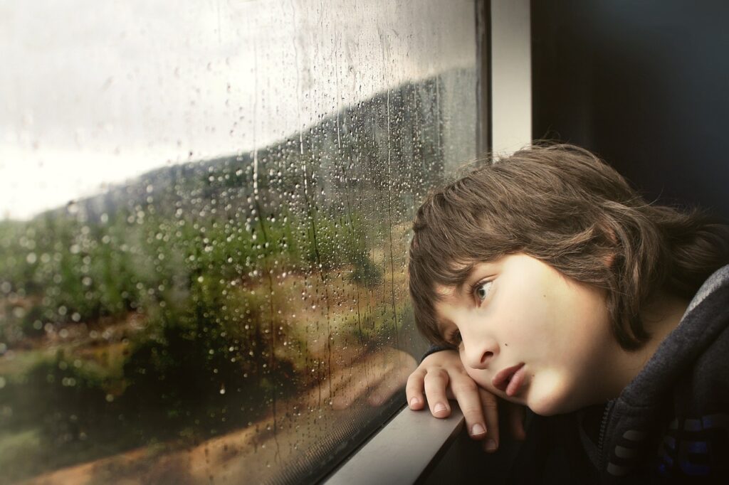 窓の外の雨を憂鬱な表情で眺めている人
